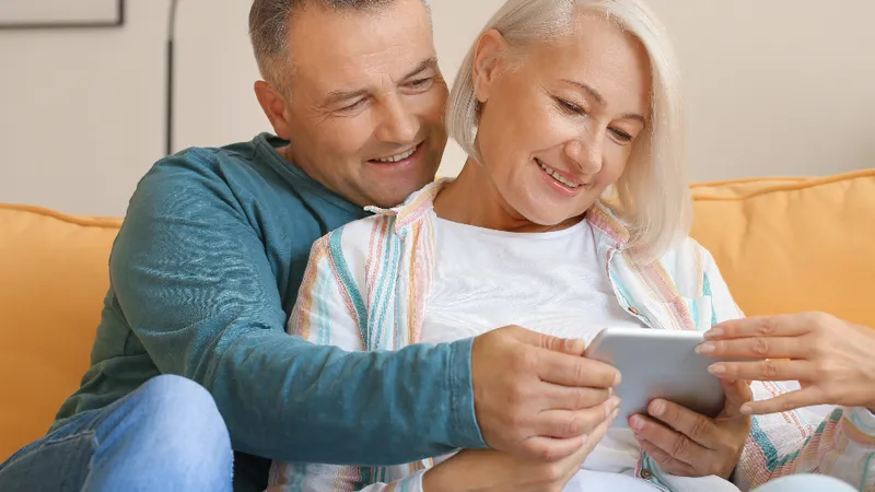 Pareja de adultos mayores sonriendo mientras revisan información juntos en su hogar